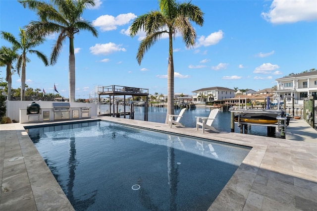 view of swimming pool featuring a water view, an outdoor kitchen, and grilling area