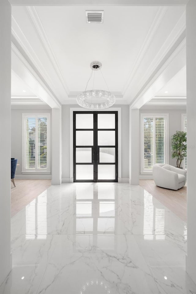 entrance foyer with crown molding, a healthy amount of sunlight, and a tray ceiling