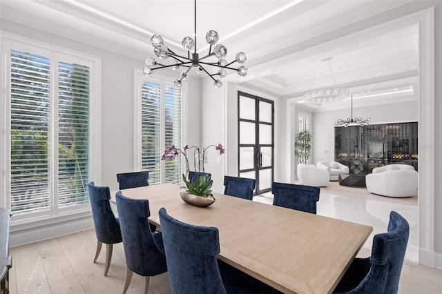 dining area featuring ornamental molding, a raised ceiling, light hardwood / wood-style floors, and a notable chandelier