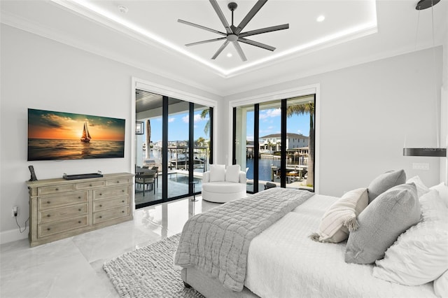 bedroom with a water view, a tray ceiling, multiple windows, and access to outside