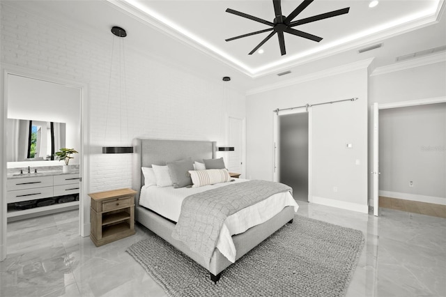 bedroom featuring crown molding, ensuite bath, a tray ceiling, and a barn door