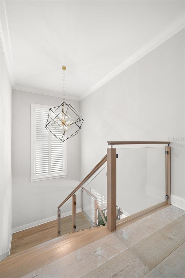 stairs with ornamental molding, a chandelier, and hardwood / wood-style floors