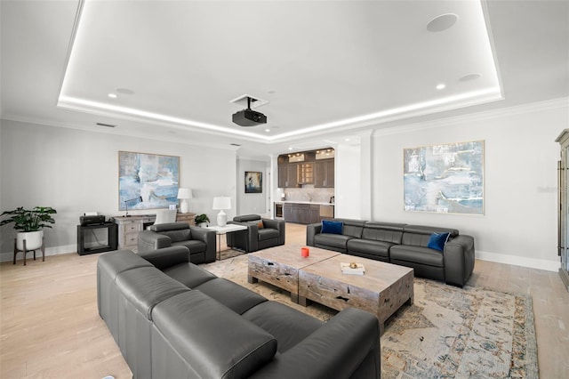 living room with crown molding, a tray ceiling, and light hardwood / wood-style flooring