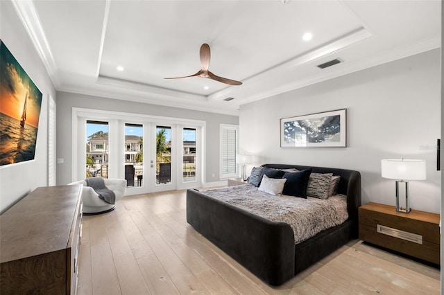 bedroom featuring french doors, crown molding, light hardwood / wood-style flooring, a tray ceiling, and access to exterior