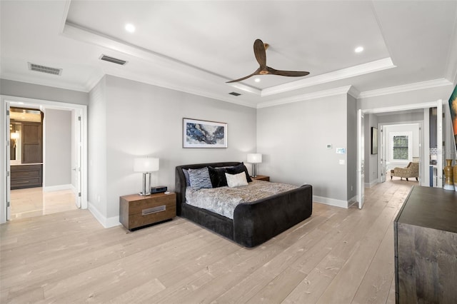 bedroom with ornamental molding, light wood-type flooring, and a tray ceiling