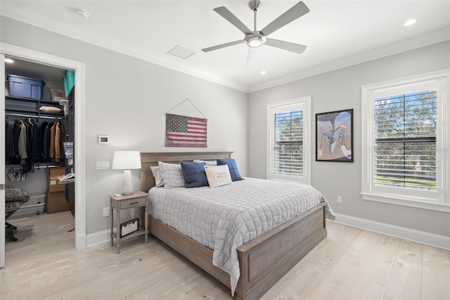 bedroom with light hardwood / wood-style flooring, a walk in closet, ceiling fan, crown molding, and a closet