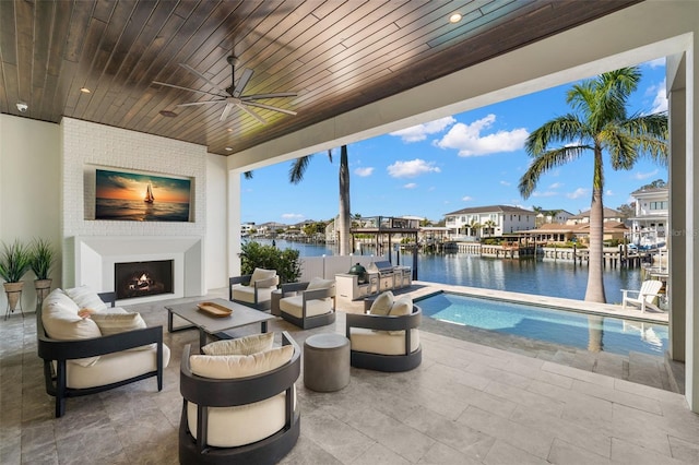 view of patio with a water view, ceiling fan, and an outdoor living space with a fireplace