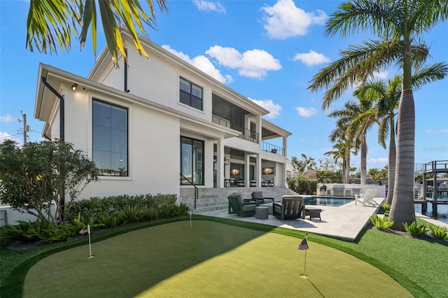 rear view of house featuring a balcony, an outdoor hangout area, a fenced in pool, and a patio area