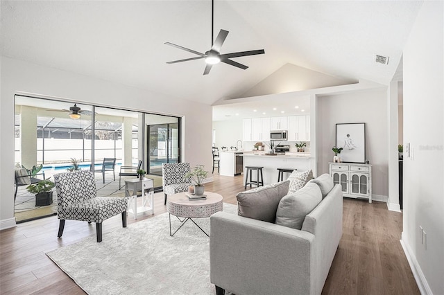 living room featuring hardwood / wood-style floors, high vaulted ceiling, and ceiling fan