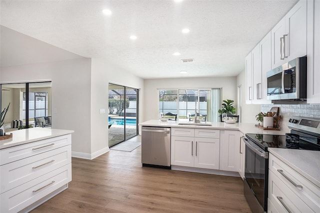 kitchen featuring sink, white cabinets, backsplash, hardwood / wood-style flooring, and stainless steel appliances