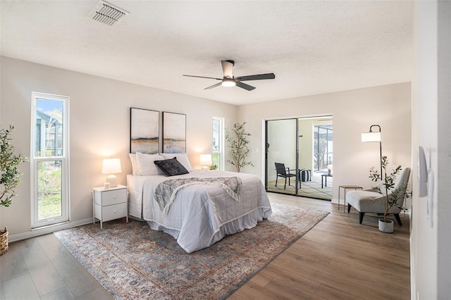 bedroom featuring wood-type flooring, ceiling fan, access to exterior, and a textured ceiling