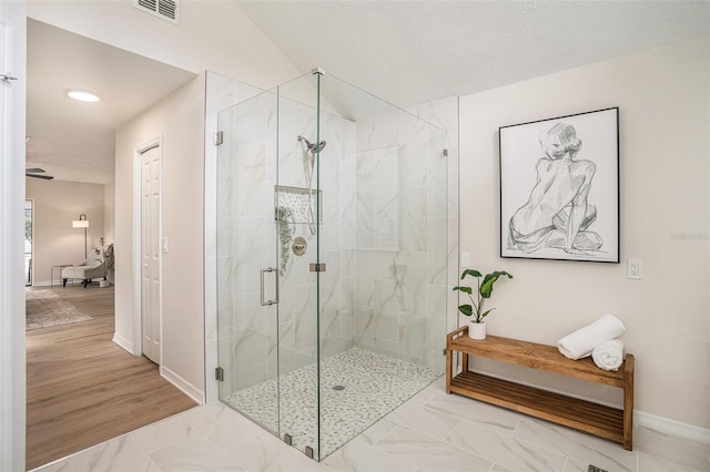 bathroom featuring a shower with door and a textured ceiling