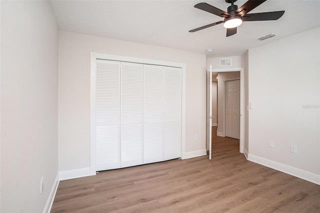 unfurnished bedroom with ceiling fan, light hardwood / wood-style flooring, a closet, and a textured ceiling