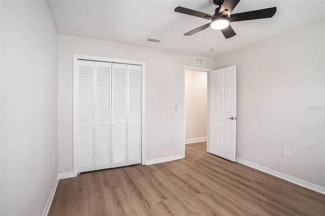 unfurnished bedroom with ceiling fan, light hardwood / wood-style floors, a closet, and a textured ceiling