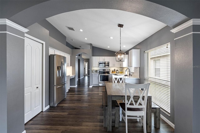 dining room featuring sink, dark wood-type flooring, and vaulted ceiling