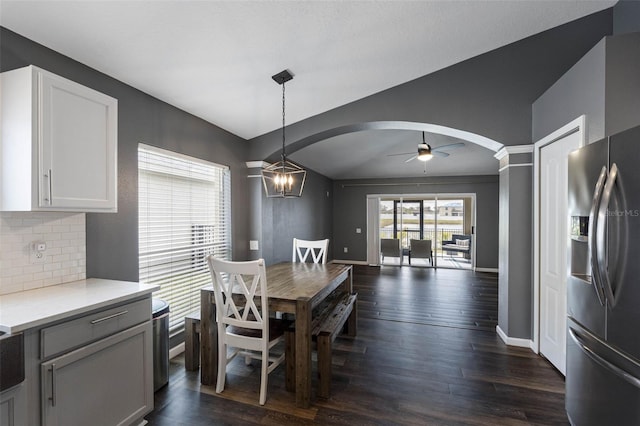 dining area featuring dark hardwood / wood-style flooring, ceiling fan with notable chandelier, and lofted ceiling