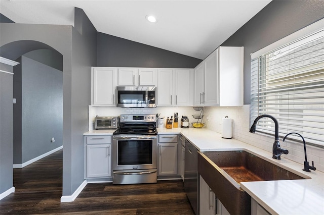 kitchen with white cabinetry, appliances with stainless steel finishes, sink, and lofted ceiling