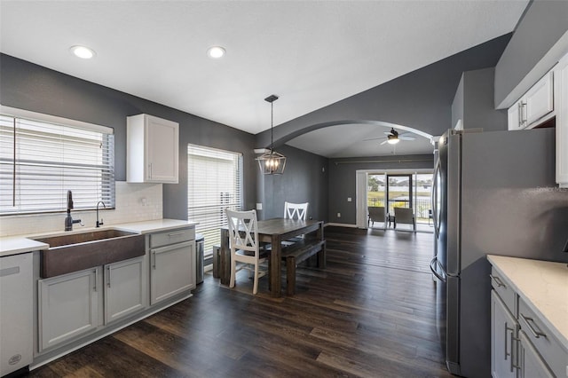 kitchen with dark wood-type flooring, sink, pendant lighting, stainless steel appliances, and white cabinets