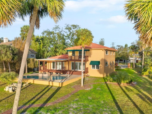 rear view of house with a balcony, a patio area, and a lawn