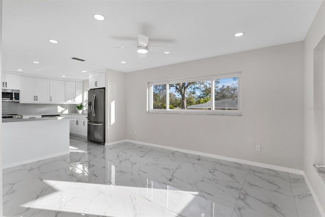 kitchen with white cabinetry, backsplash, ceiling fan, and appliances with stainless steel finishes