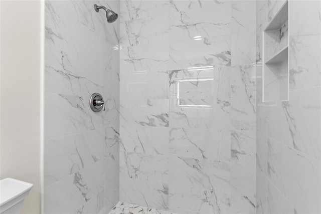 bathroom featuring tiled shower and toilet