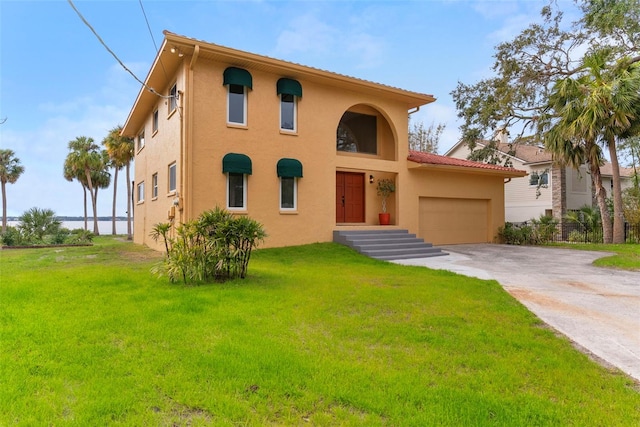 mediterranean / spanish house with driveway, a front lawn, an attached garage, and stucco siding