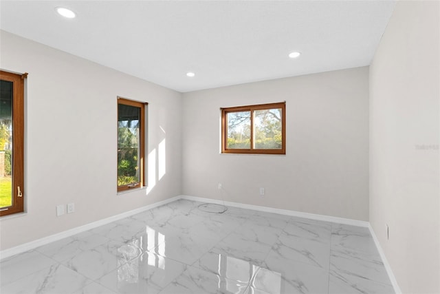 empty room featuring a wealth of natural light, marble finish floor, baseboards, and recessed lighting