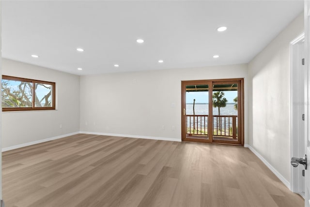 empty room featuring light wood finished floors, plenty of natural light, baseboards, and recessed lighting