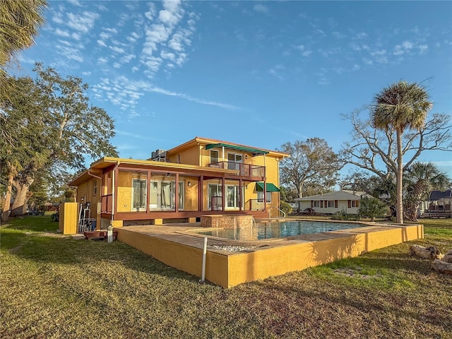 back of house featuring an outdoor pool, a lawn, and a balcony