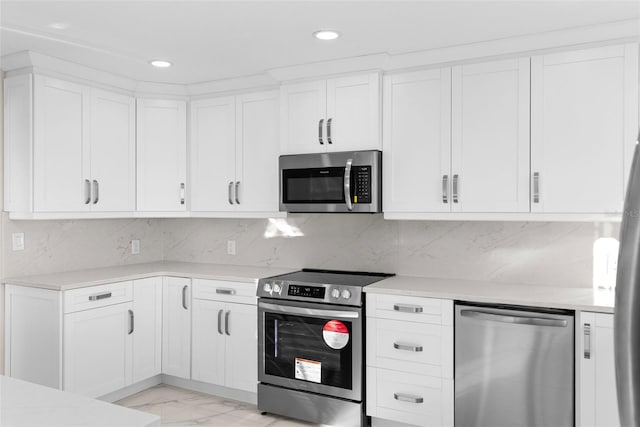 316 Shore Dr E, Oldsmar, FL 34677 - kitchen featuring light countertops, appliances with stainless steel finishes, white cabinets, and marble finish floor
