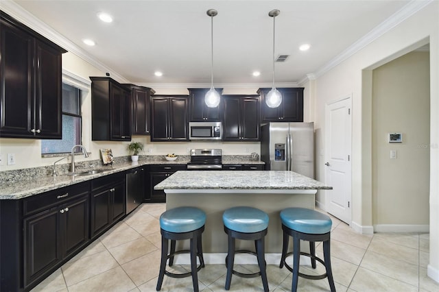 kitchen featuring sink, appliances with stainless steel finishes, a center island, light tile patterned flooring, and decorative light fixtures