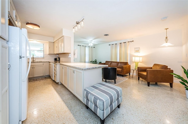 kitchen with sink, hanging light fixtures, white refrigerator, white cabinets, and kitchen peninsula