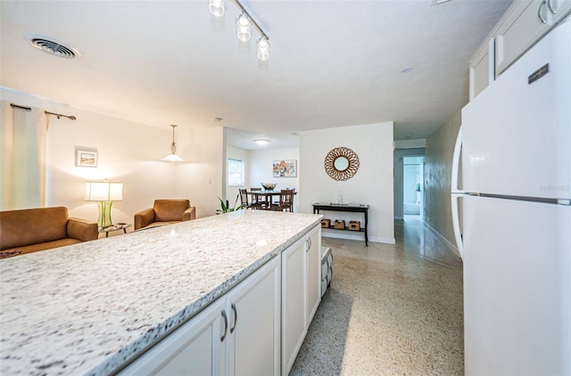 kitchen with light stone counters, decorative light fixtures, white cabinets, and white refrigerator