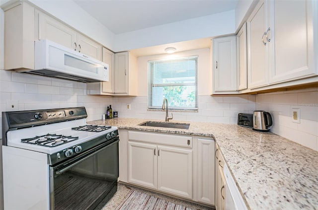 kitchen featuring white cabinetry, sink, backsplash, light stone counters, and white appliances