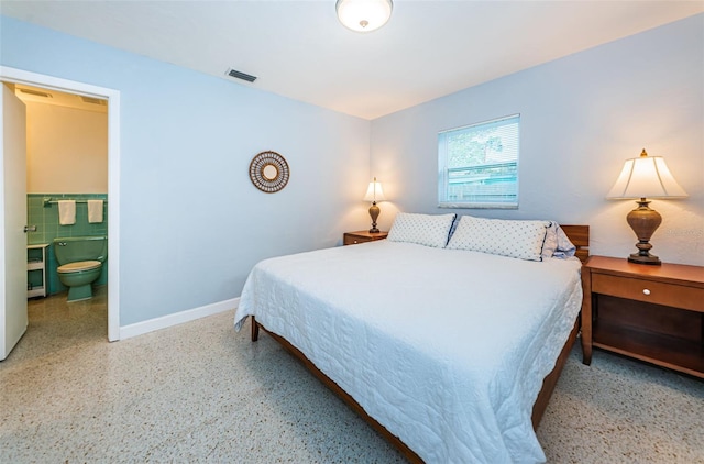 bedroom featuring connected bathroom and tile walls