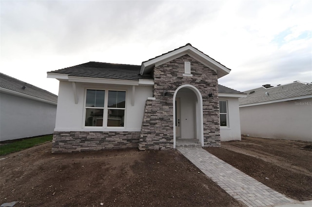 view of front facade featuring stone siding and stucco siding