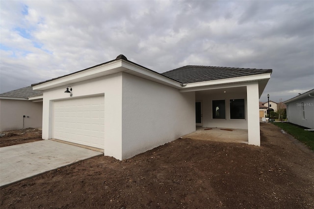 view of front of home with stucco siding, an attached garage, and driveway