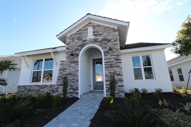 view of front of property featuring stone siding and stucco siding