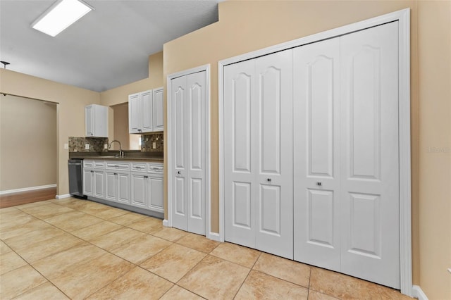 kitchen with light tile patterned flooring, sink, stainless steel dishwasher, and backsplash