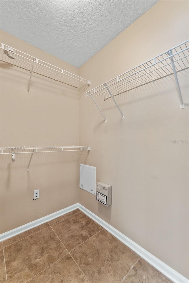 laundry area featuring tile patterned flooring and a textured ceiling