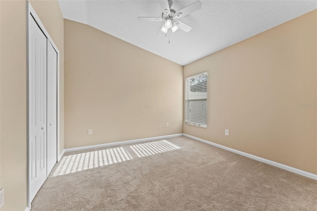 unfurnished bedroom with vaulted ceiling, light carpet, a textured ceiling, and a closet