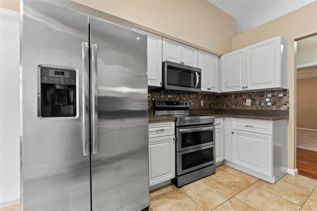 5809 War Admiral Dr, Wesley Chapel, FL 33544 - kitchen featuring appliances with stainless steel finishes, dark countertops, white cabinetry, tasteful backsplash, and light tile patterned floors