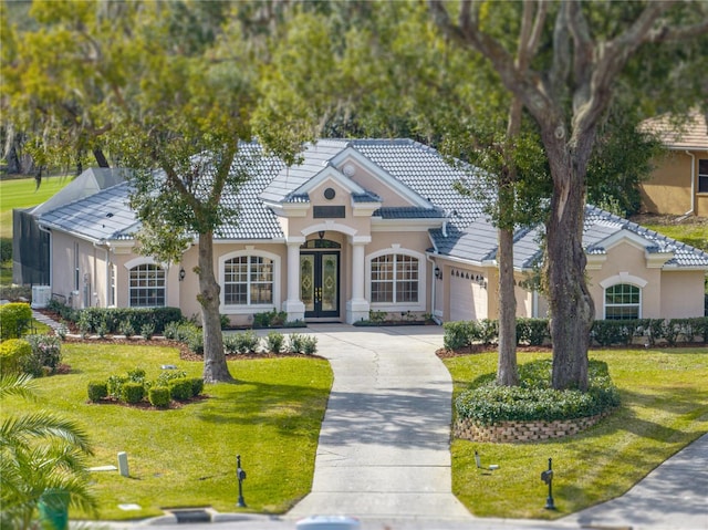 view of front facade with a garage, a front lawn, and french doors