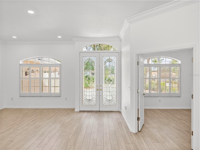 entryway with light hardwood / wood-style flooring, crown molding, and a wealth of natural light