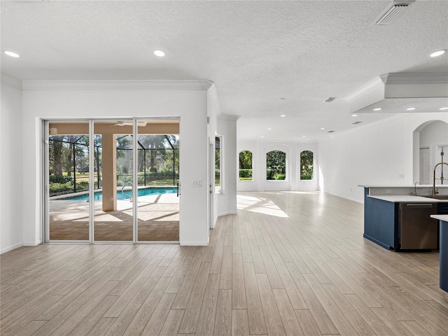 unfurnished living room featuring ornamental molding, a textured ceiling, and light wood-type flooring