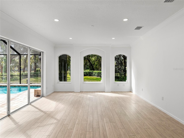 empty room featuring ornamental molding, a textured ceiling, and light hardwood / wood-style floors