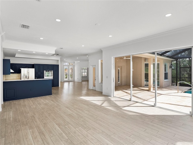 unfurnished living room featuring ornamental molding and light wood-type flooring