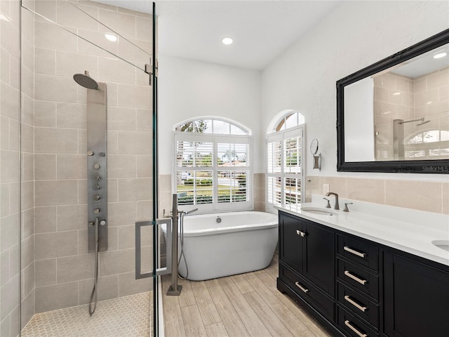 bathroom with plus walk in shower, tile walls, and vanity