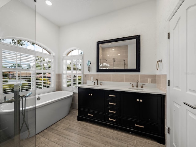 bathroom with wood-type flooring, separate shower and tub, tile walls, and vanity