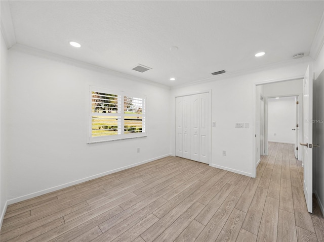 spare room with ornamental molding and light wood-type flooring